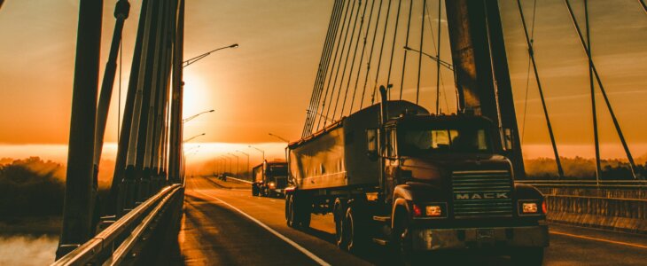 A truck crossing a suspension bridge at sunset