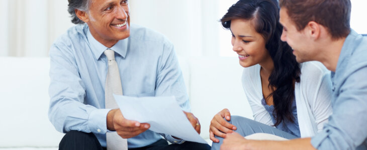 Mature advisor showing estate plan to young couple at home